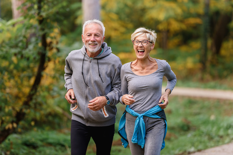 Cheerful active senior couple jogging in the park. Exercise together to stop aging.